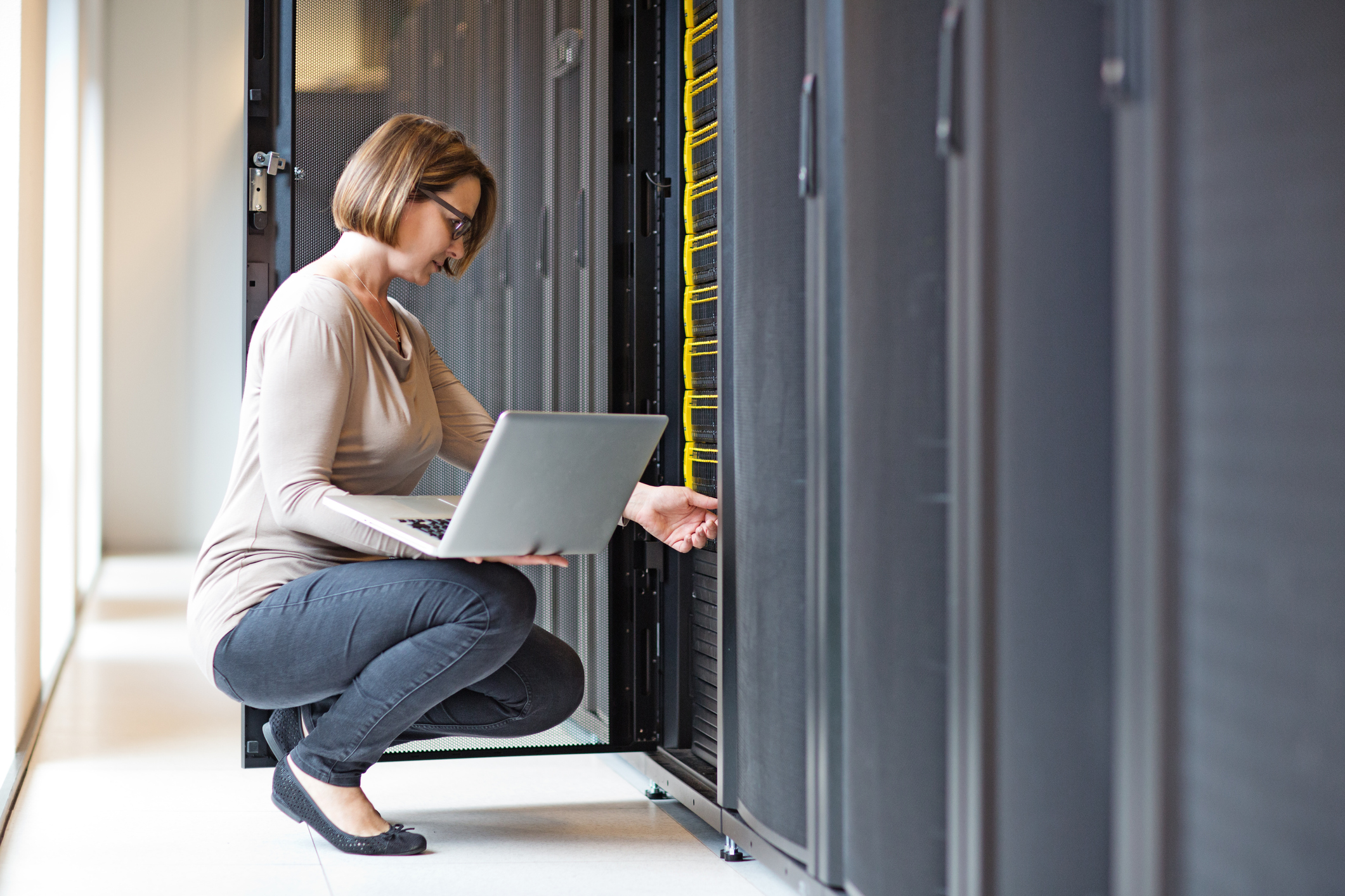 Attractive brunette adult female employee working in internet server room