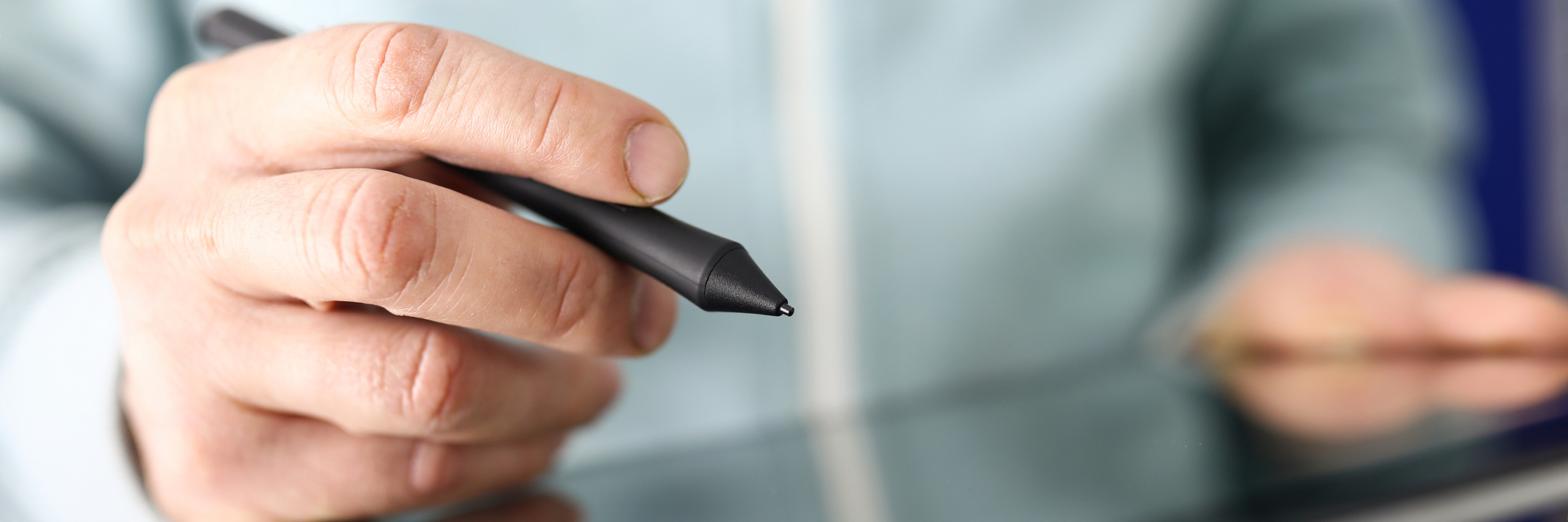 Male hand holding stylus going to make notes or seal document with digital signature close-up