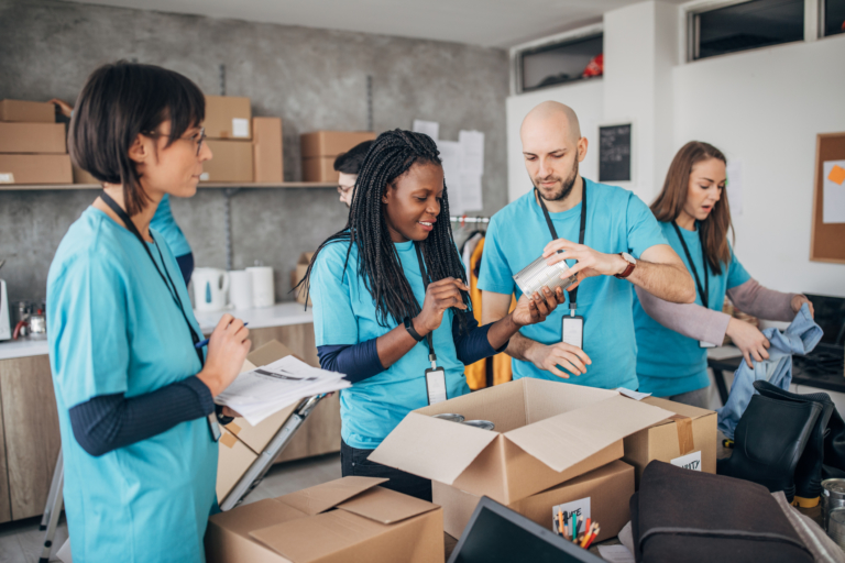 Multi-ethnic group of people, diverse volunteers packing donation boxes in charity food bank.