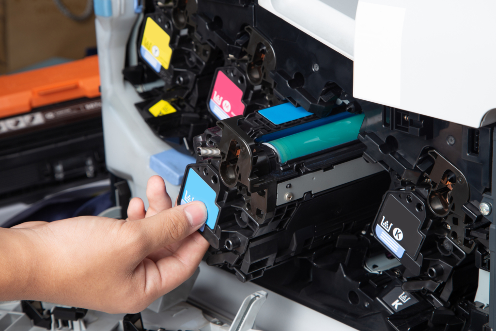 Business man or technician is checking and changing the printer equipment cartridges tone of laser jet multi function printer in the office. Close-up shot of CMYK ink cartridges for laser printer.