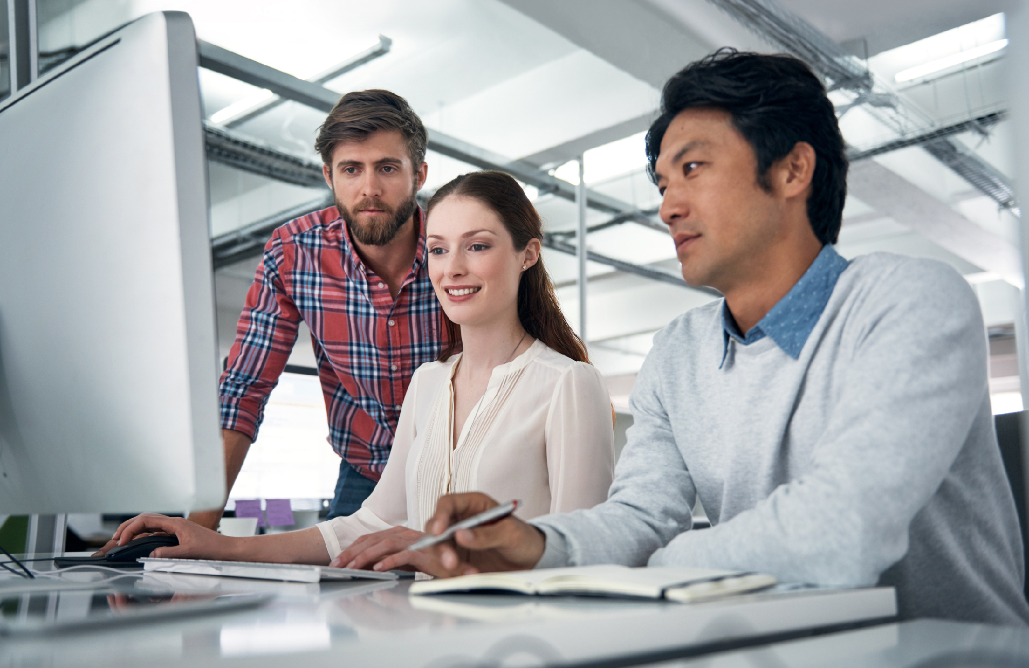 Shot of coworkers working together on a computer in an office