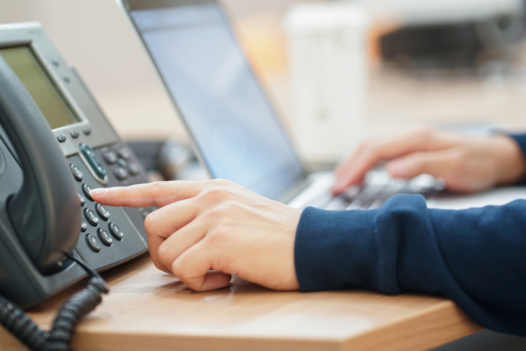 close up man hand point to press button number on telephone office desk.hotline employee concept