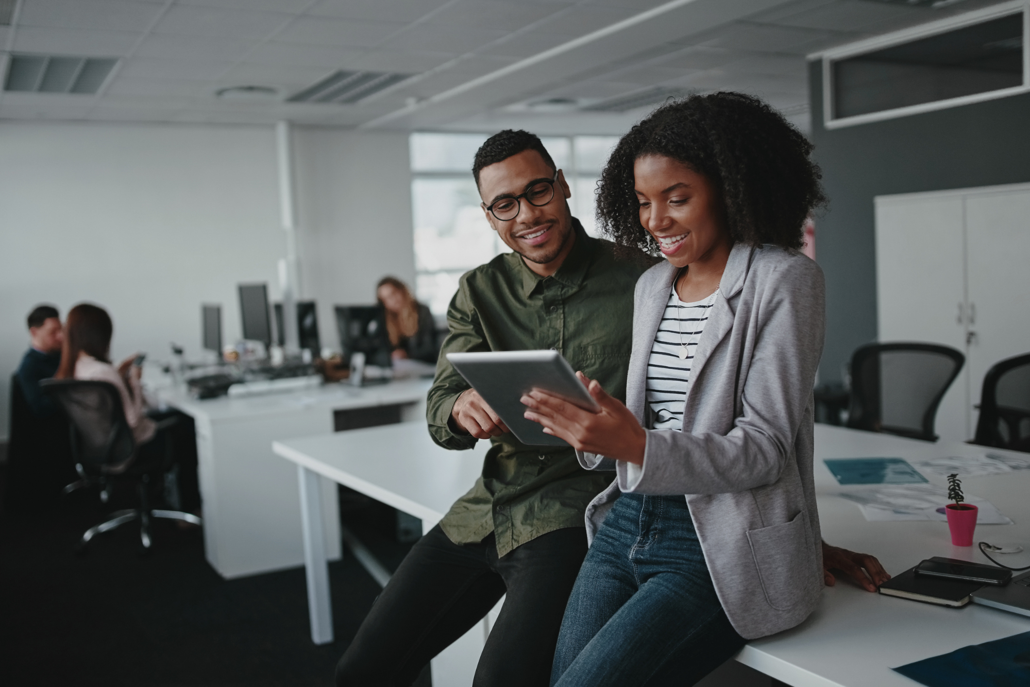 Two young professionals look at a tablet to signify cloud printing