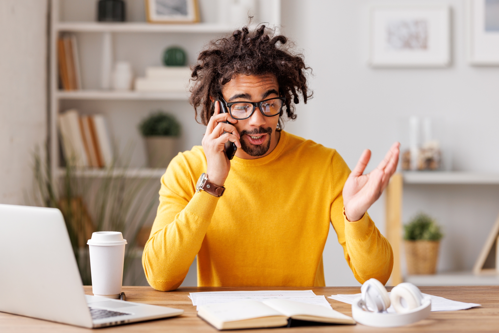 A man sitting at a home office with a laptop and phone representing remote work tools.