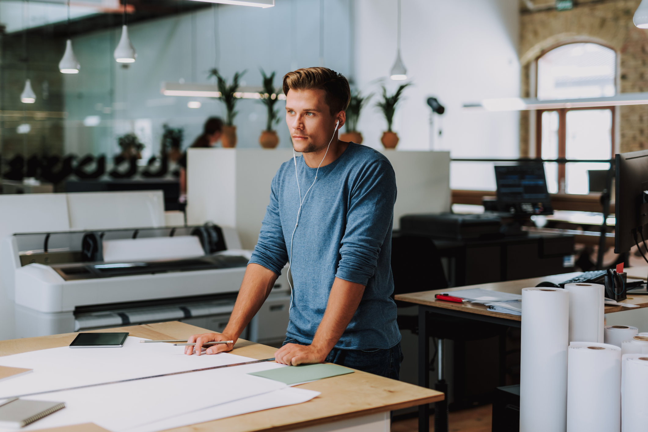 Business professional stands in front of a wide format printer