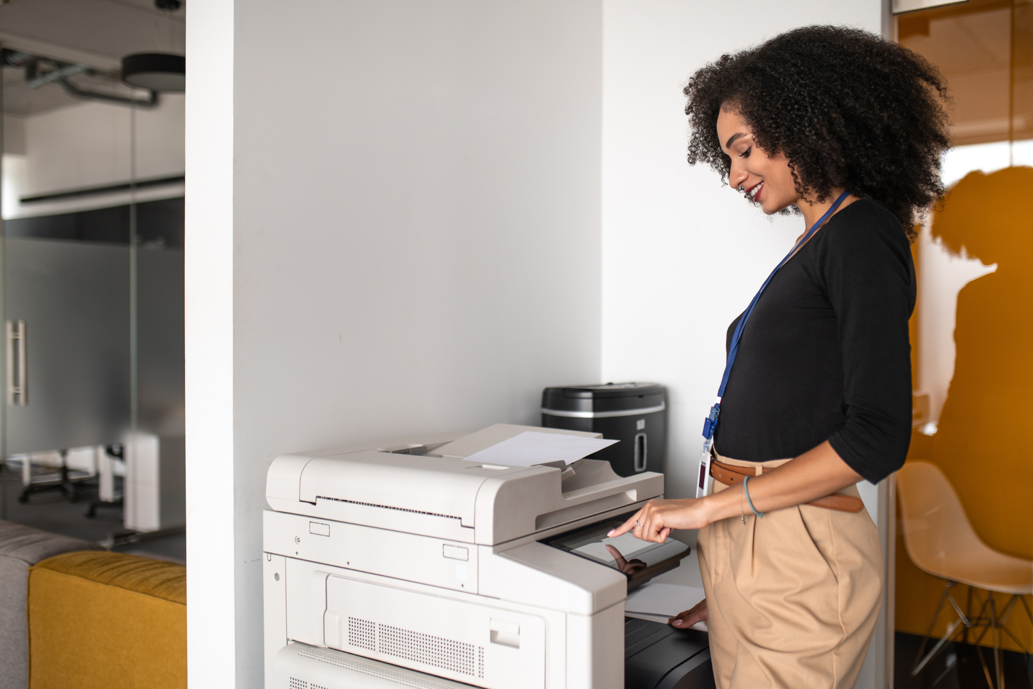 A business woman stands at an office copier interacting with the interface signifying printer service