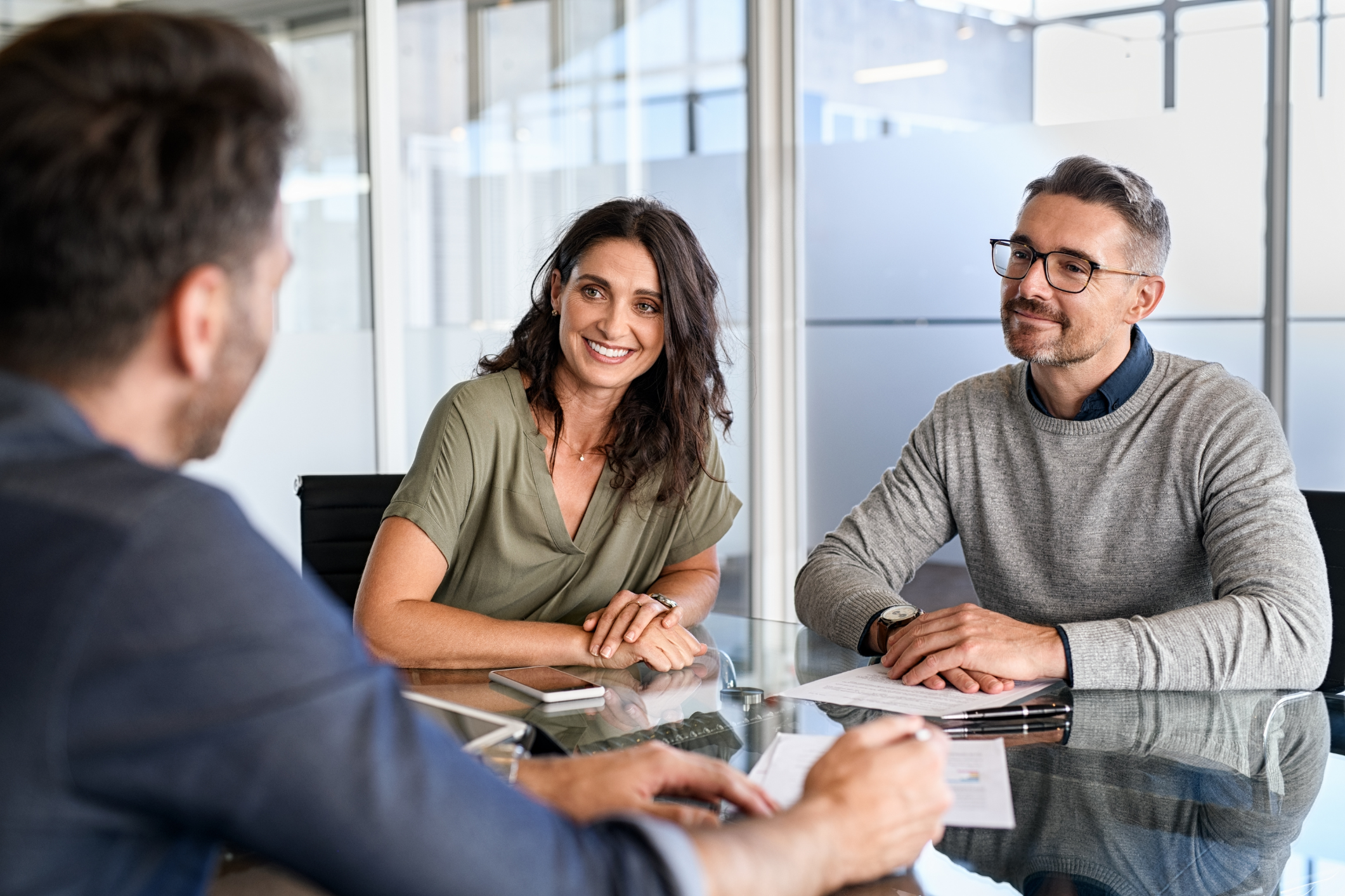 Three professionals sit at a table to review a business deal signifying a printer lease agreement