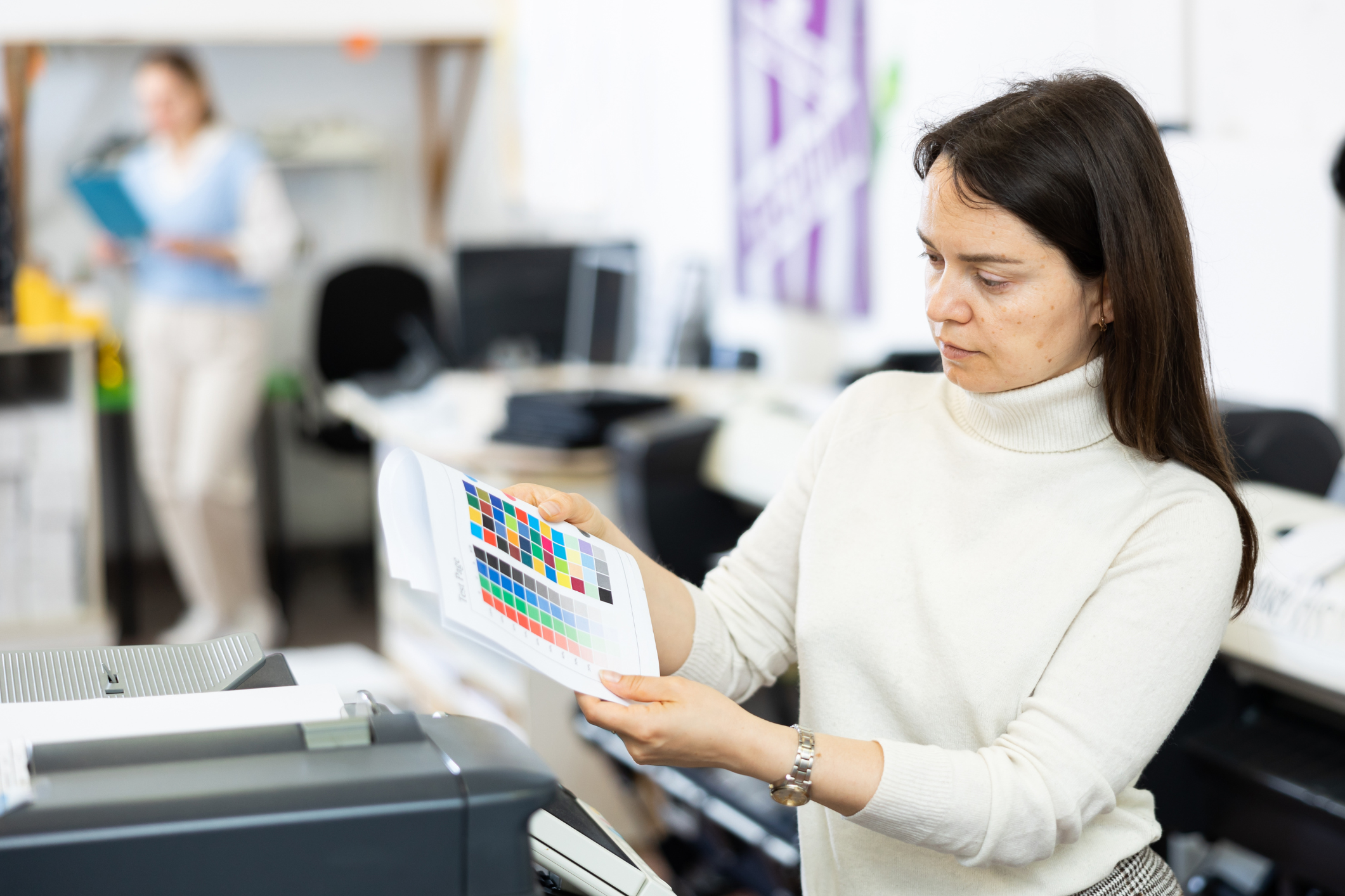 A businesswoman reviews a print output as she stands in front of an office printer.