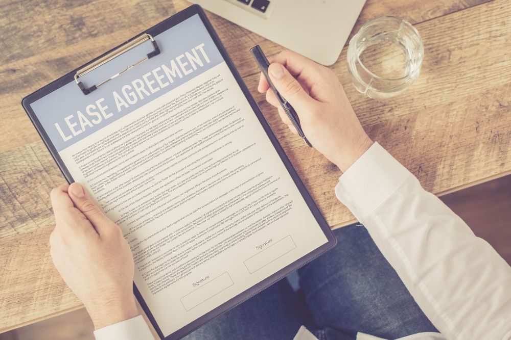 Closeup of a professional holding a pen as he reviews a lease agreement on a clipboard signifying printer leasing.